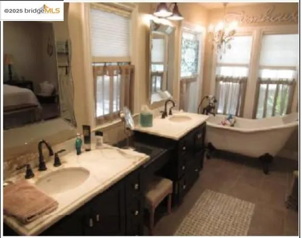 Full bath featuring connected bathroom, healthy amount of natural light, a soaking tub, and double vanity