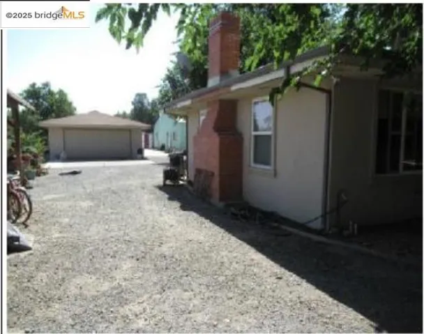 View of side of home featuring an outdoor structure, a chimney, and a garage