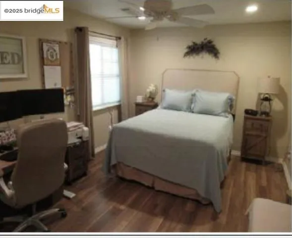Bedroom featuring ceiling fan, an office area, and wood finished floors