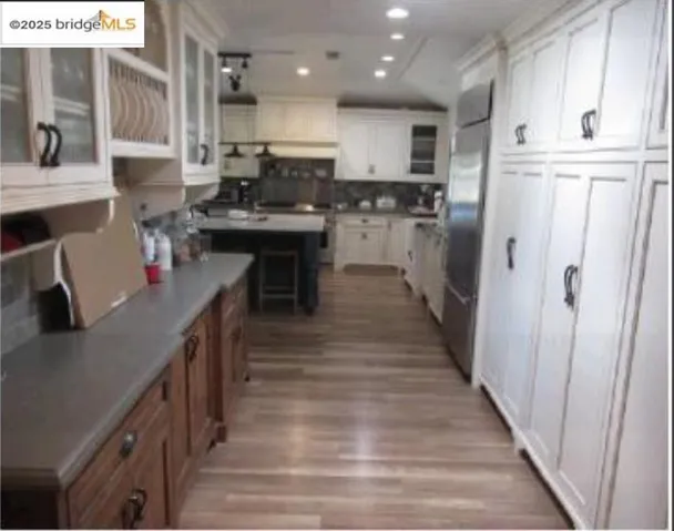 Kitchen featuring glass insert cabinets, white cabinets, light countertops, recessed lighting, and light wood finished floors