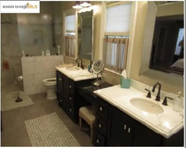 Full bathroom featuring double vanity, tiled shower, and tile walls