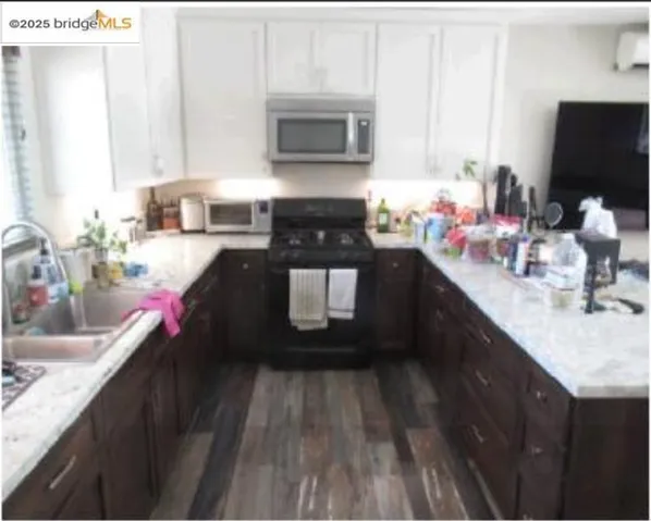 Kitchen featuring black gas stove, stainless steel microwave, white cabinetry, dark wood-style floors, and an AC wall unit