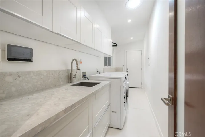 Amazing laundry room has an addition, sitting beyond washer/dryer is a second massive cabinet with large counter for gift wrapping station or crafts, with storage cabinetry beneath counter. Exterior door leads to a side patio