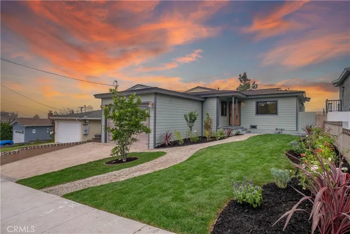 The professionally landscaped front yard creates a striking first impression, featuring lush greenery, manicured lawn, new Carrotwood Tree, new Green Gage Plum Tree & new Apple Tree that complements the home's exterior.