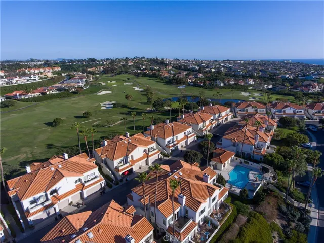 Aerial views over golf course, lake on golf course, community pool & spa facing south with ocean just beyond.