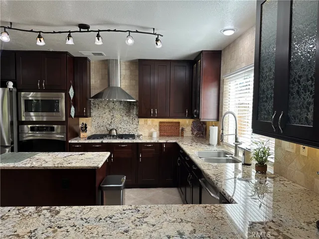 close up view  of granite large  counter tops  and stainless steel bell shape hood