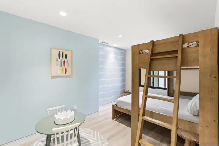The guest bedroom feels like a private retreat, soft coastal light over linen textures, a quiet reading nook, and serene garden views that ease every arrival.