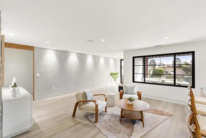 The Family room centers on a large glass window that draws in coastal light and breezes, washing quiet oak and soft textiles in a calm, contemporary glow.