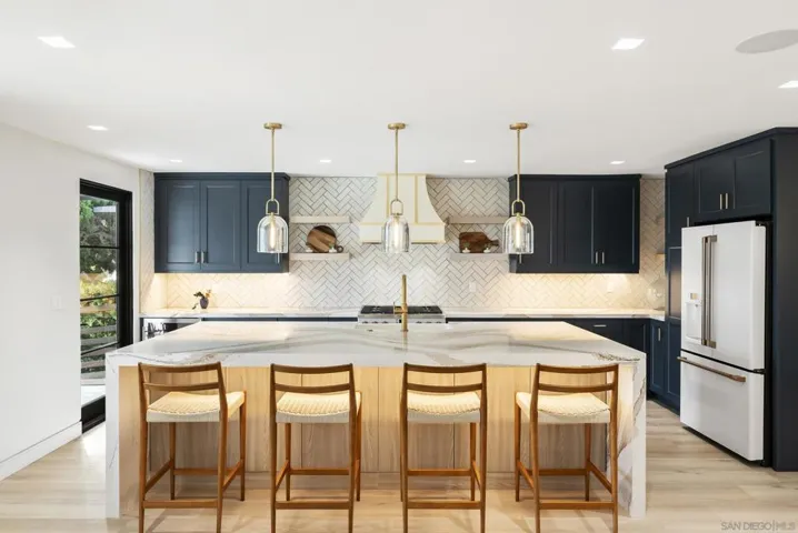 A sculptural kitchen with an island, concealed storage, and glass that washes sleek worktops in San Diego sun.