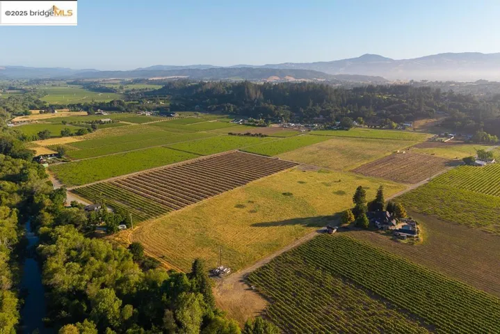 Aerial view of property and surrounding area with a mountain backdrop, rural landscape, and large plots for crops