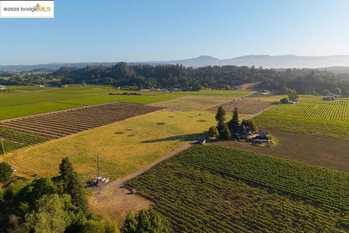 Aerial view of property and surrounding area featuring mountains, rural landscape, and abundant farmland
