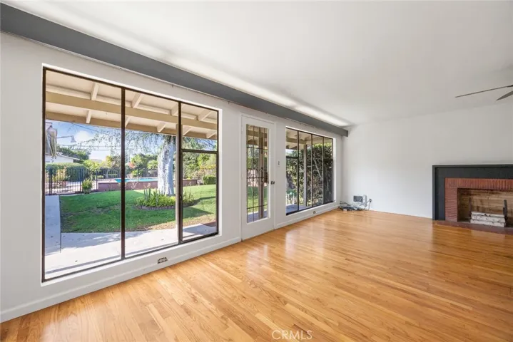 Looking out from the formal dining room at 10357 Lesterford Avenue onto the living room fireplace, the yard and the pool.