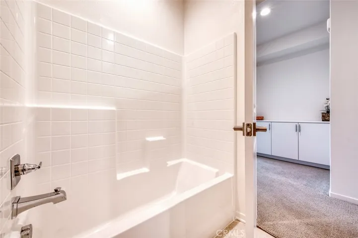 Upstairs hall bathroom has bathtub with shower, white cabinetry and quartz counters.