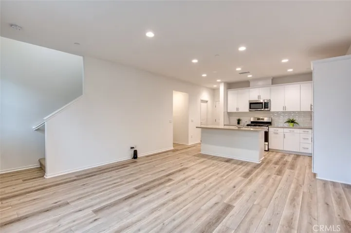 Open concept living room and kitchen with quartz counters, breakfast bar island and custom cabinetry.