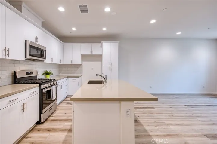 Open kitchen with quartz counters, breakfast bar island and custom cabinetry.