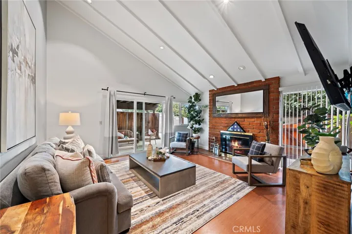 Living room features vaulted, beamed ceilings and an abundance of natural light streaming through a large sliding door