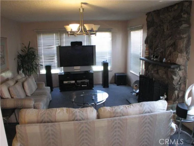Open ,well lit living room with floor to ceiling rock fireplace