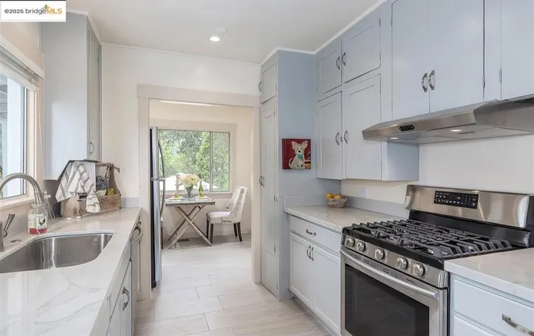 Kitchen featuring appliances with stainless steel finishes, under cabinet range hood, light stone countertops, and recessed lighting