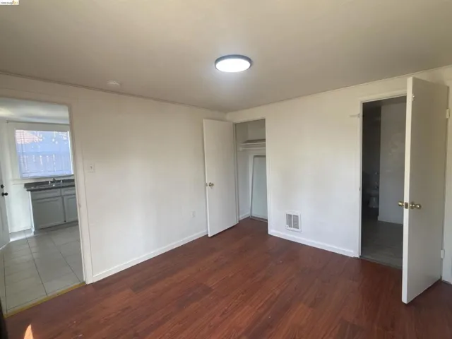 Unfurnished bedroom featuring dark wood-style flooring, crown molding, and a closet