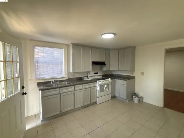 Kitchen with white range with electric stovetop, light tile patterned flooring, and gray cabinets
