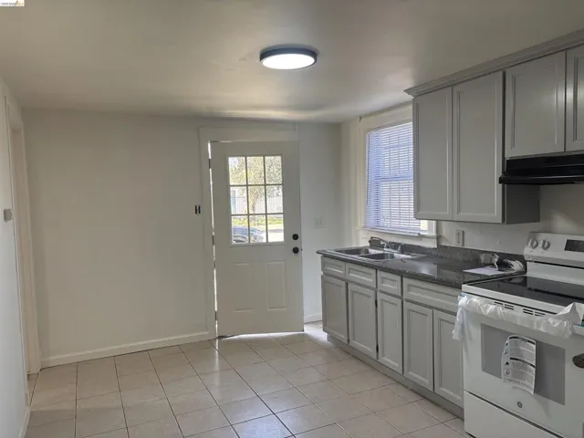 Kitchen featuring white electric range, light tile patterned flooring, and gray cabinets