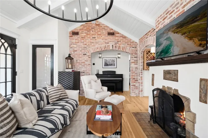 The light-filled living room is framed by large windows overlooking the lush gardens and centers around a welcoming fireplace—perfect for relaxing or entertaining.