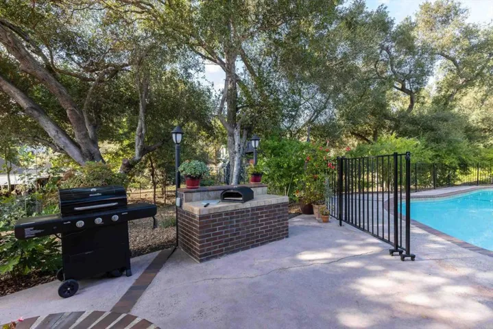 Couple sliding panels of rod iron fence slide open in a stacking way for large entrance to pool