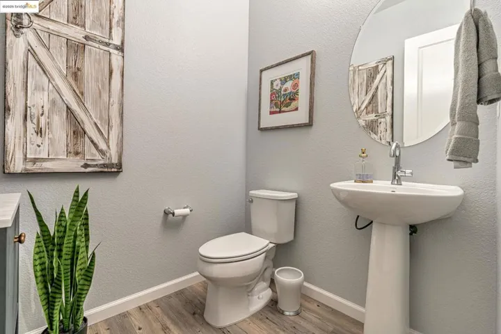 Half bath featuring a textured wall and light wood-style floors