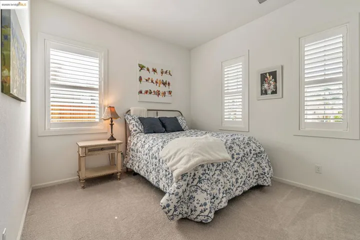 Bedroom with light carpet and multiple windows