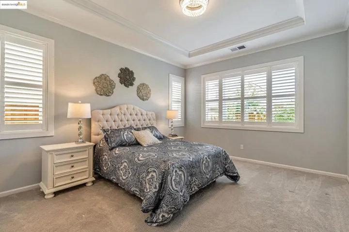 Bedroom with carpet, a tray ceiling, and ornamental molding