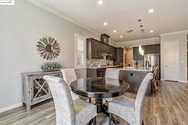 Dining room with ornamental molding, light wood-style floors, and recessed lighting