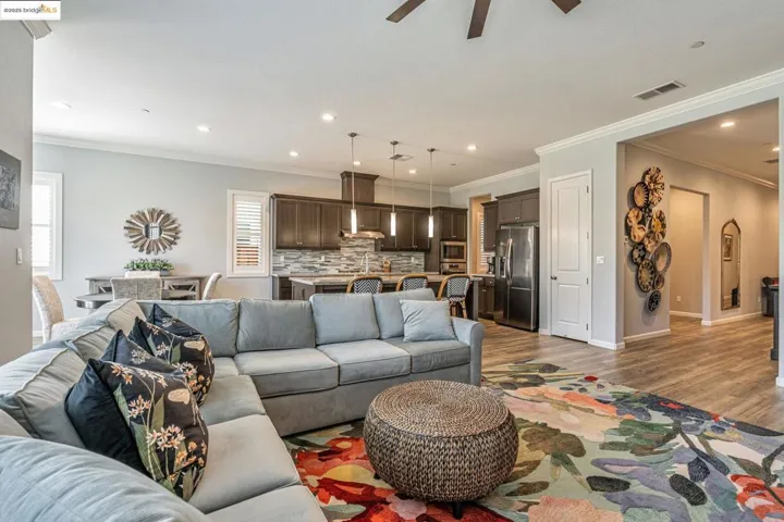 Living area with ornamental molding, recessed lighting, a ceiling fan, and wood finished floors
