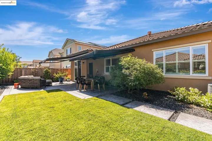 Back of property with a fenced backyard, stucco siding, a patio area, an outdoor living space, and a tiled roof