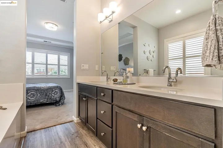 Full bathroom featuring double vanity, ensuite bathroom, light wood-type flooring, and light colored carpet