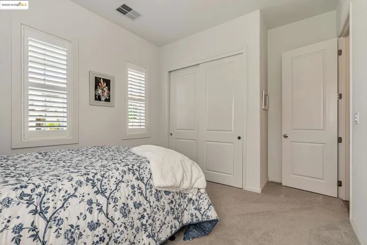 Bedroom with light colored carpet and a closet