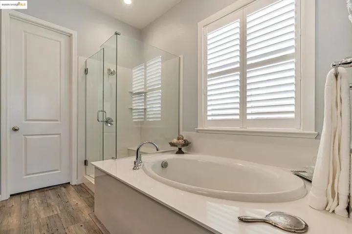 Full bathroom featuring a shower stall, a bath, and light wood-style floors