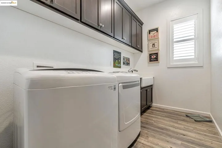 Washroom featuring light wood-type flooring, washer and dryer, cabinet space, and a textured wall