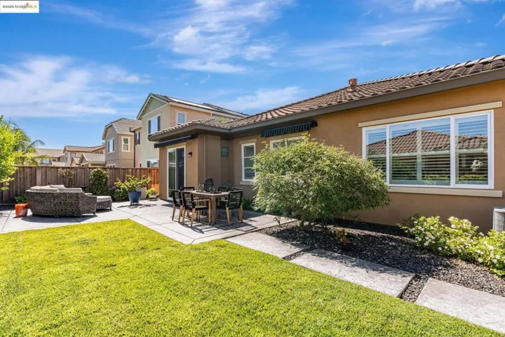 Back of property with stucco siding, a patio area, a tile roof, and an outdoor living space