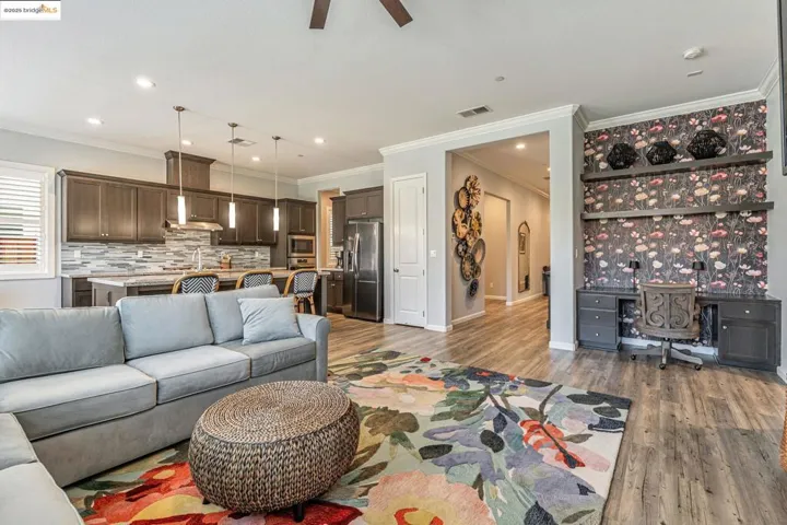Living area featuring wood finished floors, ornamental molding, recessed lighting, a ceiling fan, and built in study area