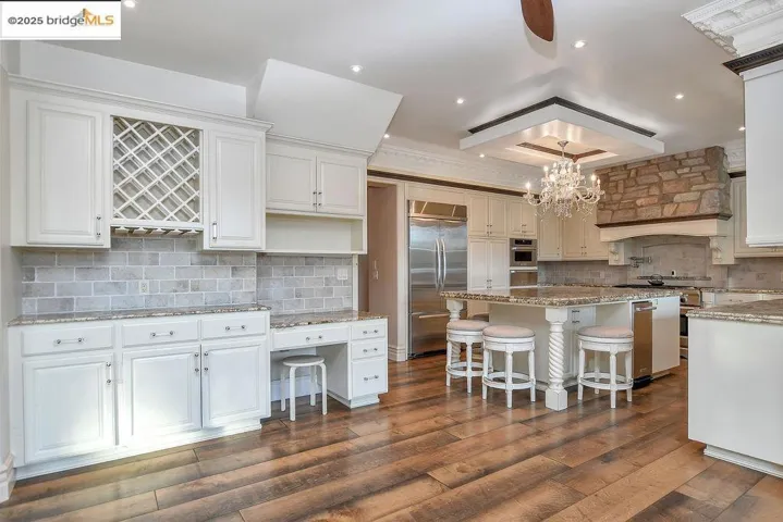 Kitchen with light stone countertops, stainless steel appliances, backsplash, recessed lighting, and a breakfast bar area