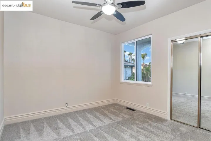 Unfurnished bedroom with light carpet, a closet, and a ceiling fan