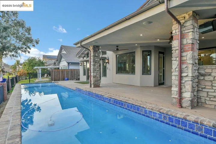 View of swimming pool with ceiling fan and a patio area