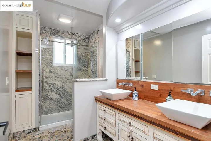 Full bathroom with double vanity, a shower stall, and decorative backsplash