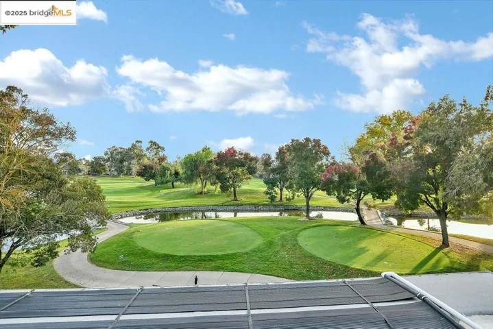 View of home's community featuring a putting green, golf course view, view of scattered trees, and a water view