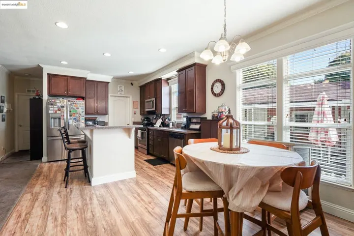 Kitchen with a kitchen breakfast bar, stainless steel appliances, crown molding, dark brown cabinetry, and light wood finished floors