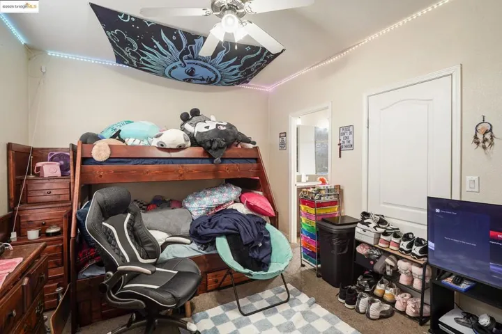 Bedroom with carpet floors, ceiling fan, and an office area