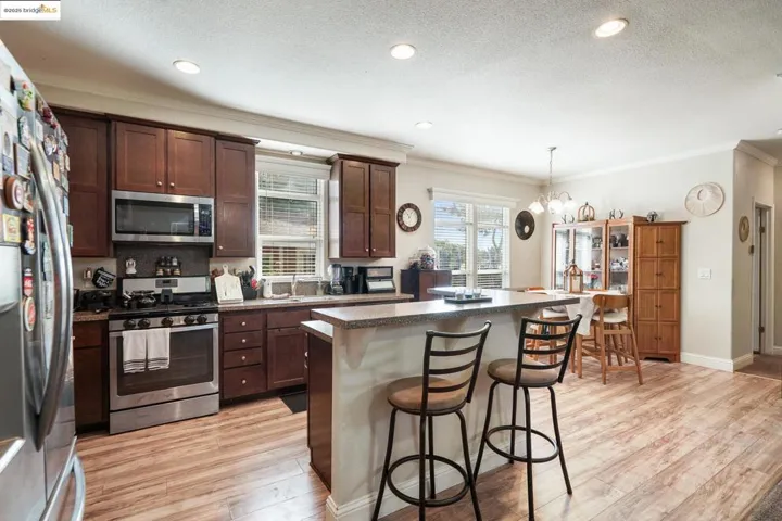 Kitchen featuring a breakfast bar, appliances with stainless steel finishes, ornamental molding, dark countertops, and light wood-style flooring