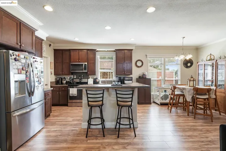 Kitchen featuring stainless steel appliances, crown molding, a kitchen breakfast bar, a center island, and light wood finished floors