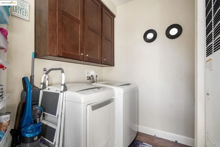 Laundry room featuring cabinet space, dark wood-type flooring, a heating unit, washer and dryer, and a textured wall