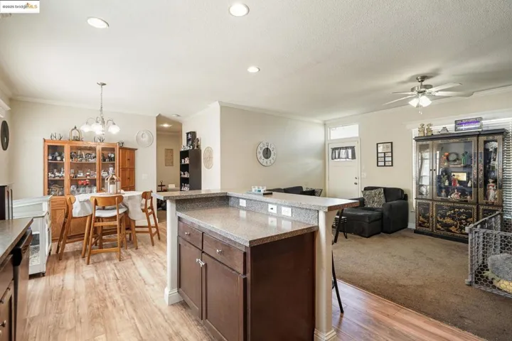 Kitchen with dark brown cabinetry, a kitchen bar, open floor plan, decorative light fixtures, and ornamental molding